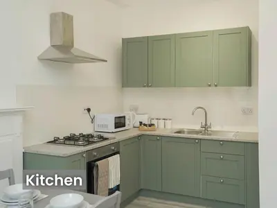 a kitchen with green cabinets and a microwave at Edinburgh Modern Apartment in Haymarket, city centre in Edinburgh