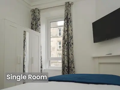 a bedroom with a bed and a tv and a window at Edinburgh Modern Apartment in Haymarket, city centre in Edinburgh