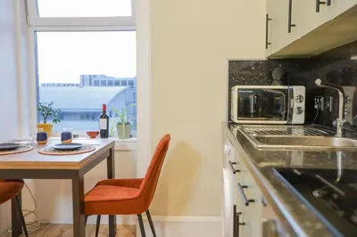 a kitchen with a table with chairs and a microwave at Cosy City Centre Gem in Edinburgh