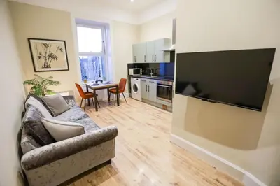 a living room with a couch and a kitchen with a table at Cosy City Centre Gem in Edinburgh