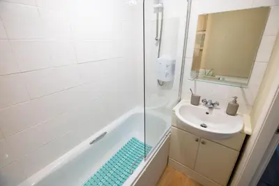 a white bathroom with a sink and a shower at Cosy City Centre Gem in Edinburgh