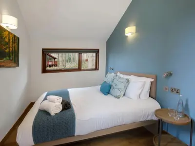 a bedroom with a large white bed with blue walls at Strathyre, Ben Ledi Cabins - Forest Holidays in Callander