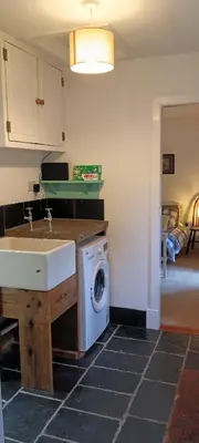 a kitchen with a sink and a washing machine at Red Deer Cottage at Fanans in Oban