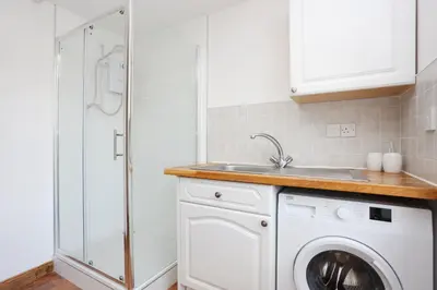 a kitchen with a washing machine and a sink at JOIVY Greenknowes Farmhouse with Hot Tub and Bar in Kelty