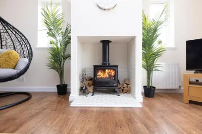 a living room with a fireplace and a tv at JOIVY Greenknowes Cottage with Hot Tub & Fireplace in Kelty