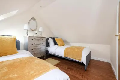 a bedroom with two beds and a dresser at JOIVY Greenknowes Lodge with Hot Tub and Wood Burning Stove in Kelty