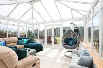 a conservatory with a living room with a glass ceiling at JOIVY Greenknowes Estate with Hot Tub and Bar - Farmhouse and Lodge in Kelty