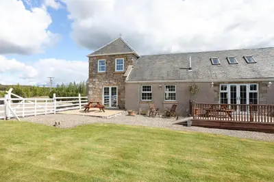 an old stone house with a deck and a yard at JOIVY Greenknowes Estate with Hot Tub and Bar - Farmhouse and Lodge in Kelty