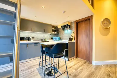 a kitchen with blue cabinets and a bar stool at Union Court Mezzanine - B9 - Building has no lift and stairs to all apartments in Glasgow
