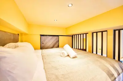 a bedroom with a large bed with yellow walls and windows at Union Court Mezzanine - B9 - Building has no lift and stairs to all apartments in Glasgow