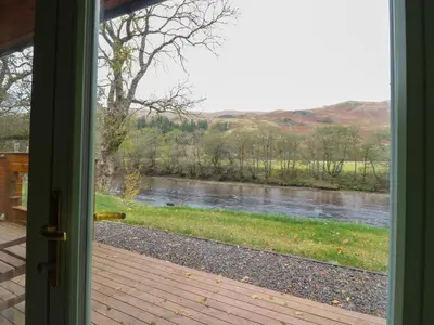 a door open to a view of a river at Bradan Lodge in Dalmally