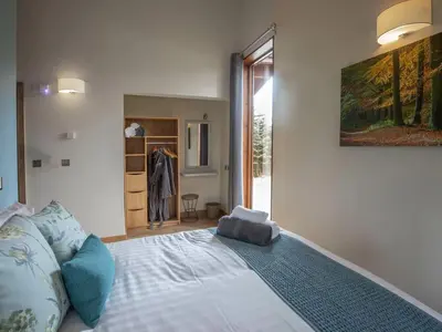 a bedroom with a bed with a painting on the wall at Ardgartan Argyll Cabins - Forest Holidays in Arrochar