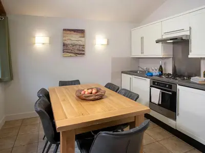 a kitchen with a wooden table with a bowl of fruit on it at Ardgartan Argyll Cabins - Forest Holidays in Arrochar