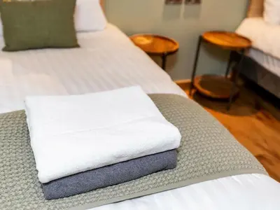 a white towel sitting on a bed in a room at Ardgartan Argyll Cabins - Forest Holidays in Arrochar