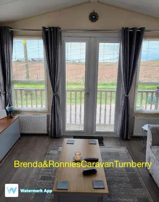 a living room with large windows and a coffee table at B&R 18 Gleneagles in Turnberry