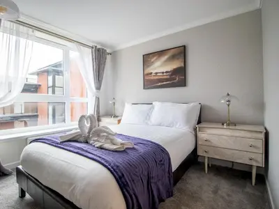 a bedroom with a bed with a teddy bear on a blanket at Metropolitan St Andrews Cathedral View - Pass the Keys in Glasgow