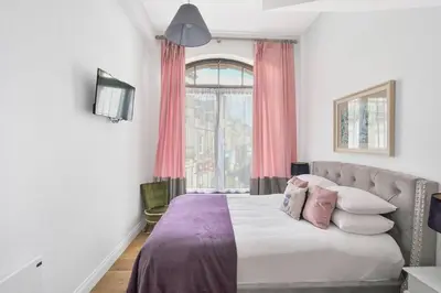 a bedroom with a large bed with pink curtains at Alloa City Centre in Alloa