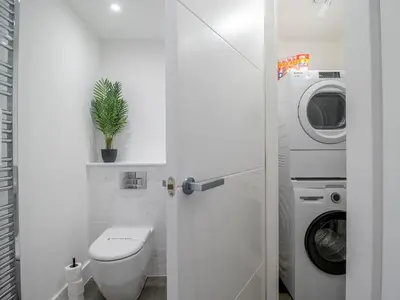 a bathroom with a toilet and a washing machine at Fabulous Festival Park Home Private Parking Garden - Pass the Keys in Glasgow