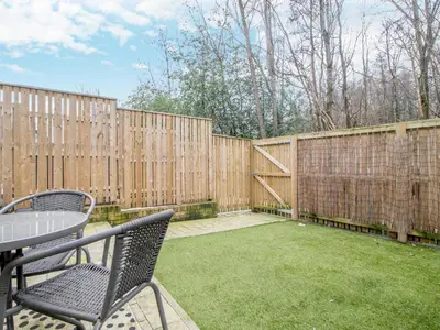 a backyard with a fence and a table and chairs at Fabulous Festival Park Home Private Parking Garden - Pass the Keys in Glasgow