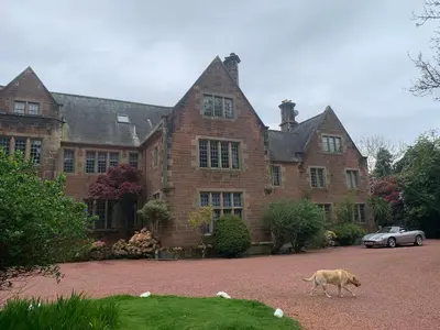 a dog walking in front of a large house at Lovely Carlung House in West Kilbride