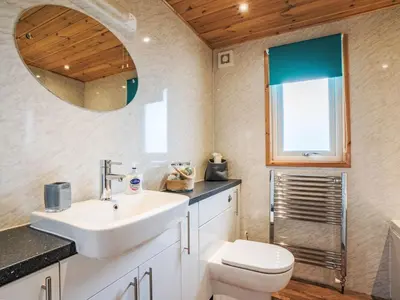 a bathroom with a sink and a toilet and a mirror at Chalet Loch Leven Lodge 21 by Interhome in Kinross