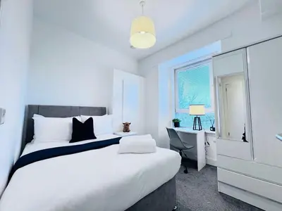 a white bedroom with a large bed and a desk at Elegant City Centre Apartment in Edinburgh