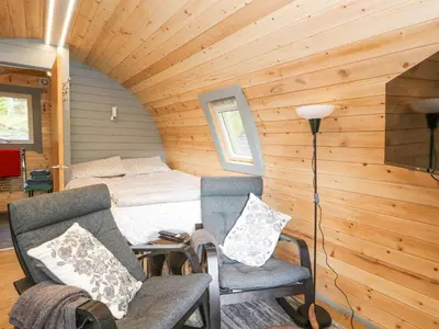 a room with a bed and two chairs in a cabin at Elleric Pods - The Last Resort in Appin