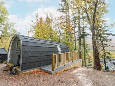 a small cabin with a porch and a wooden deck at Elleric Pods - The Last Resort in Appin