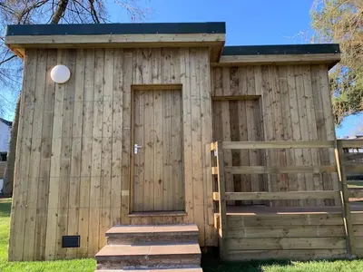 a wooden building with two doors and a fence at North Lodge Glamping in Carnwath