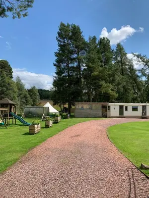 a gravel driveway with a playground and a park at North Lodge Glamping in Carnwath