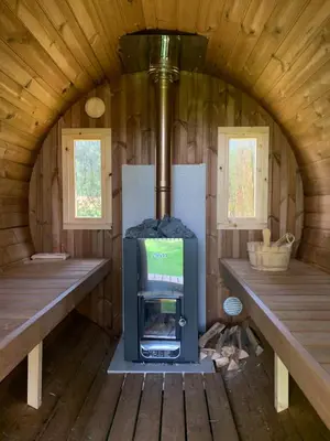 a wood stove in a cabin with two benches at North Lodge Glamping in Carnwath