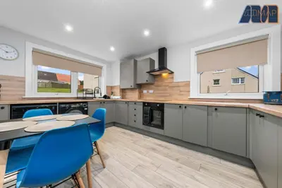 a kitchen with a table and some blue chairs at Cosy 2-Bed House I Easy Edinburgh Access I Sleeps 4 in Whitburn