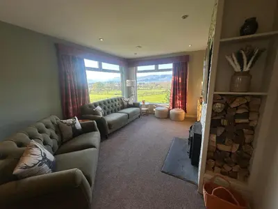 a living room with couches and a large window at Ardenvhor - Loch Lomond in Gartocharn