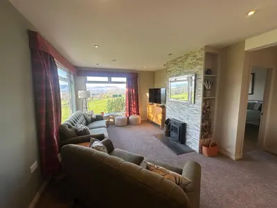 a living room with two couches and a fireplace at Ardenvhor - Loch Lomond in Gartocharn