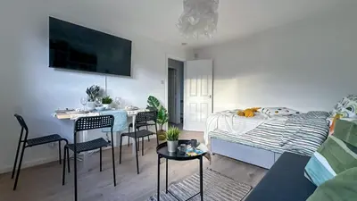 a living room with a bed and a table and chairs at Cosy stylish Duntocher flat near Glasgow in Clydebank