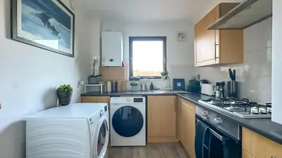 a kitchen with a washing machine and a washer at Cosy stylish Duntocher flat near Glasgow in Clydebank