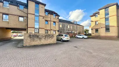 a car parked in a parking lot next to a building at Cosy stylish Duntocher flat near Glasgow in Clydebank