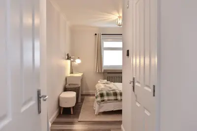 a small bedroom with a bed and a window at Barassie Bay View apartment in Troon