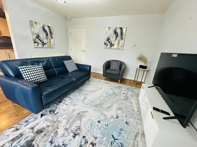 a living room with a black leather couch and a television at Modern Economy Glasgow Apartment with King bed in Glasgow