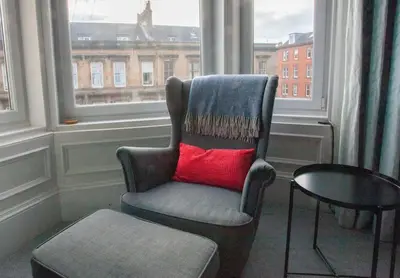 a chair with a red pillow in a room with a window at Newly Renovated Flat in Trendy Finnieston in Glasgow