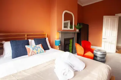 a bedroom with a white bed and an orange wall at Newly Renovated Flat in Trendy Finnieston in Glasgow