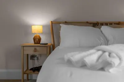a bed with white sheets and a lamp on a night stand at GuestReady - Charming home in Edinburgh in Edinburgh