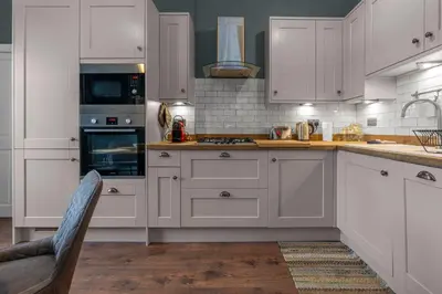 a kitchen with white cabinets and a stove top oven at GuestReady - Charming home in Edinburgh in Edinburgh