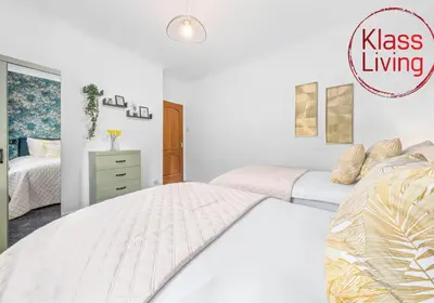 a white bedroom with two beds and a dresser at Oxford Apartment by Klass Living in Coatbridge