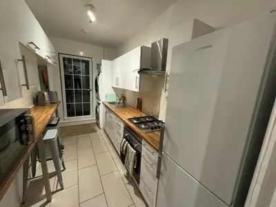 a kitchen with white cabinets and a stove top oven at Stirling Haven: Charming 3B Apt in City Centre in Stirling