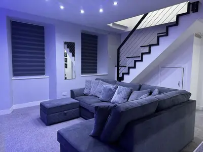 a living room with a couch and a staircase at Modern 3-Bedroom Home with Cozy Cinema-Style Living Space in Cumbernauld