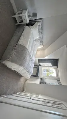 a room with a bed with pillows and a window at Modern 3-Bedroom Home with Cozy Cinema-Style Living Space in Cumbernauld