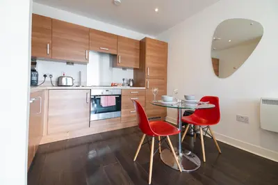 a kitchen with a table and two red chairs at Argyle Apartment in Glasgow