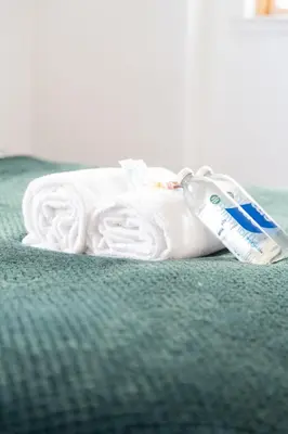 a white towel and a bottle of tooth paste on a bed at Argyle Place in Glasgow