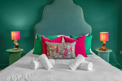 a white bed with colorful pillows and two lamps at GuestReady - Unique hideaway in Edinburgh in Edinburgh